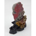 A Chinese soapstone carving of flowers, raised on a naturalistic base. H.