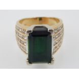 A green tourmaline dress ring, set in a yellow metal band with diamond set shoulders, 10 g.