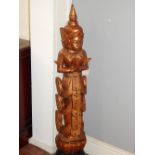 An Indo-China carved wooden deity at prayer standing on a lotus blossom,