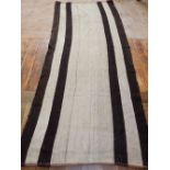 A North African tent rug, brown strips on cream ground, 260 x 109cm.