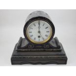 A late Victorian black slate mantel clock, the white enamel dial set out with Roman numerals,