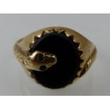 A 9ct yellow gold and onyx set ring, the band fashioned as a snake with garnet set eyes, 5.2g.