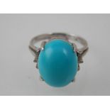 A cabouchon turquoise dress ring, the oval stone claw set in a platinum band.