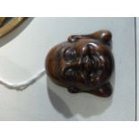 A carved hardwood netsuke, modelled in the form of a happy monk, the reverse bearing a signed disk,