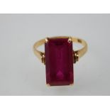 A tourmaline dress ring, the rectangular faceted red stone claw set in a yellow gold band.