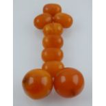 A collection of nine loose amber coloured beads of varying shapes and sizes.