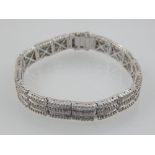 An 18 carat white gold and diamond articulated segment bracelet, set alternating round cut and