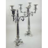 A pair of plated candleabrums, having three scrolling arms above column and foliate base. H.