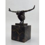 A contemporary bronze of a nude crouching man, arms outstretched and palms outwards,