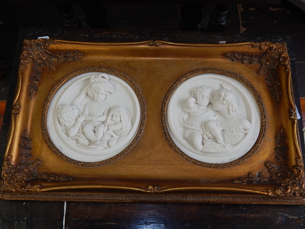 A pair of reconstituted marble plaques, one modelled in low relief with three children, D.