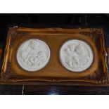 A pair of reconstituted marble plaques, one modelled in low relief with three children, D.