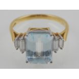 An 18 carat yellow gold Art Deco style dress ring, set with emerald cut aquamarine,