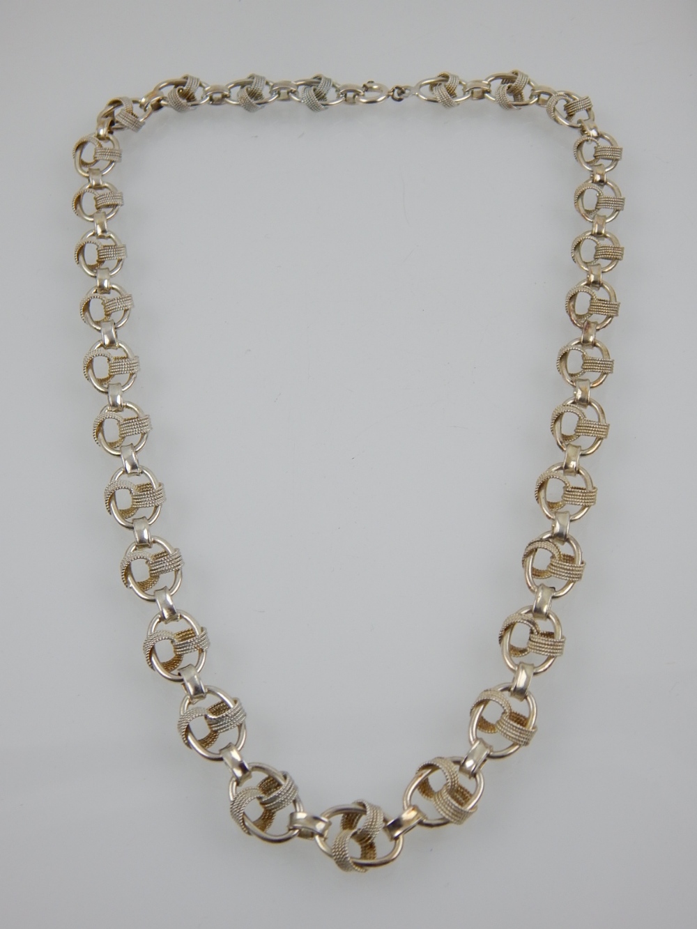 A silver necklace of knotted link design.