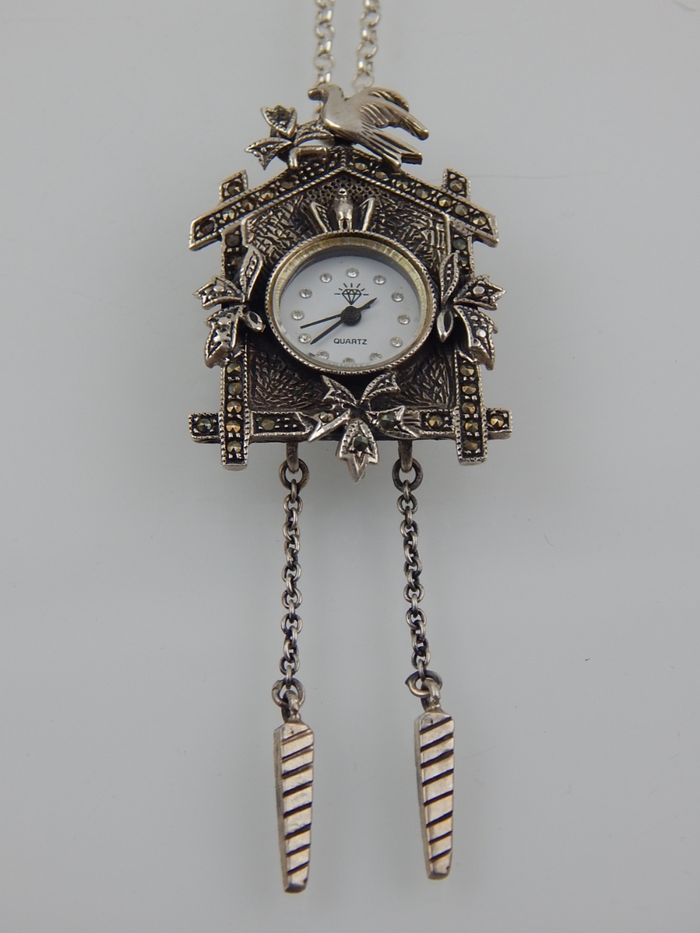 A silver quartz clock pendant, suspended on a silver chain, stamped 925.