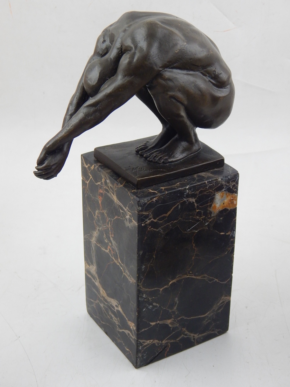 A contemporary bonze figure of a nude male athlete, in crouching, raised on a marble base, H. 24cm.