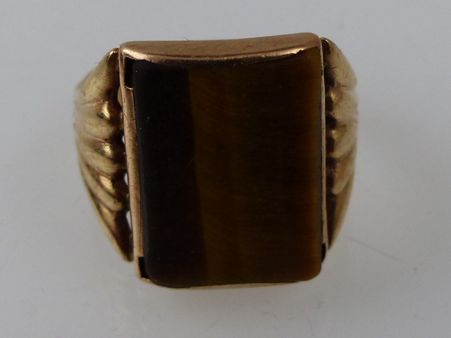 An Art Deco yellow metal and polished tigers eye dress ring, size T, 7.1g, stamped 9ct.