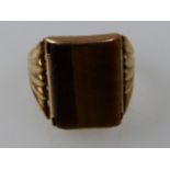 An Art Deco yellow metal and polished tigers eye dress ring, size T, 7.1g, stamped 9ct.