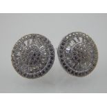 A pair of silver and cubic zirconia cluster earrings, set round and baguette stones.