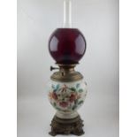 A late Victorian lamp, with a ceramic reservoir incorporating floral decoration and brass mounts,