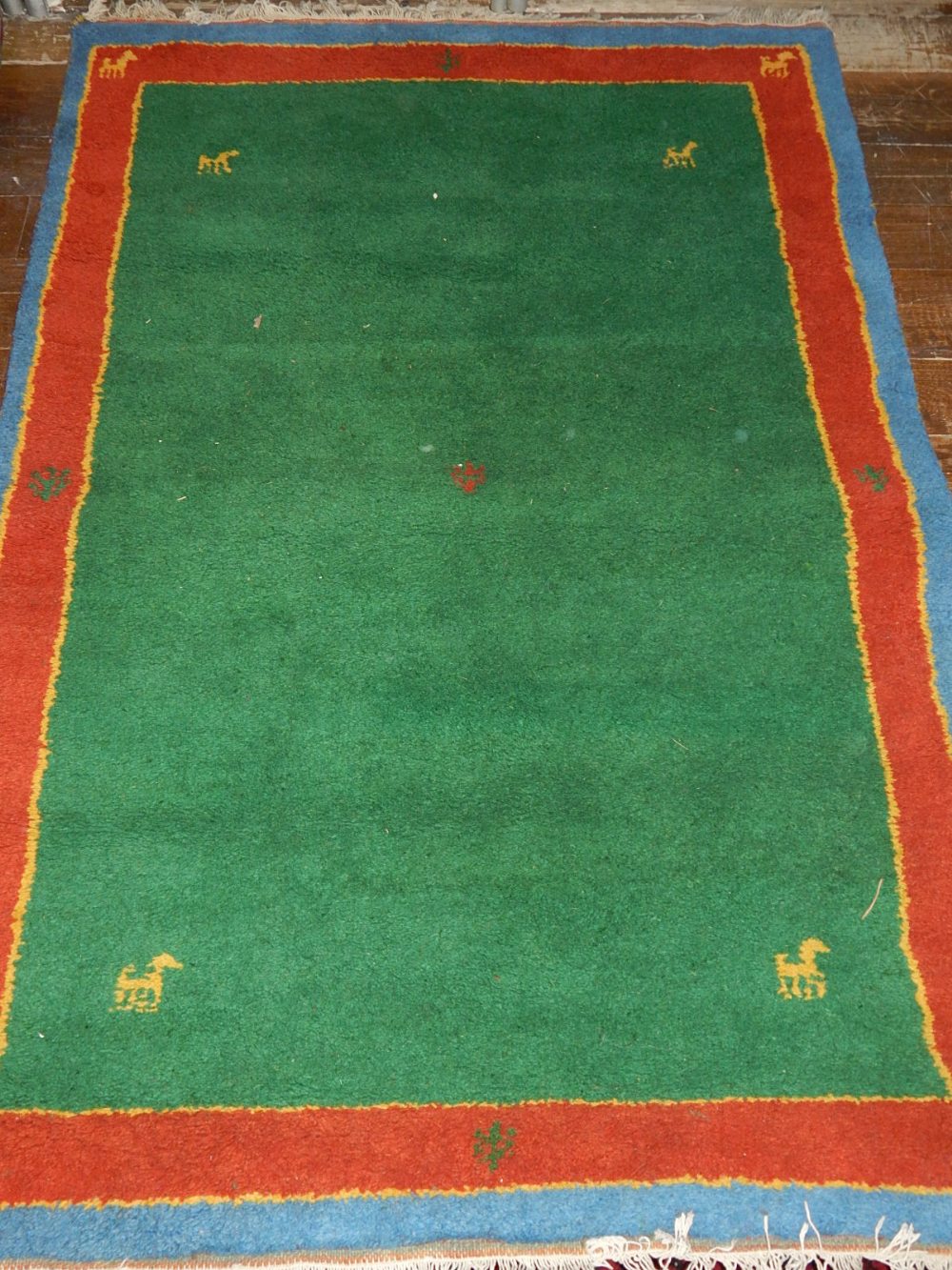 A green ground Gabbeh rug, decorated with stylised animals, within yellow, red and blue border,