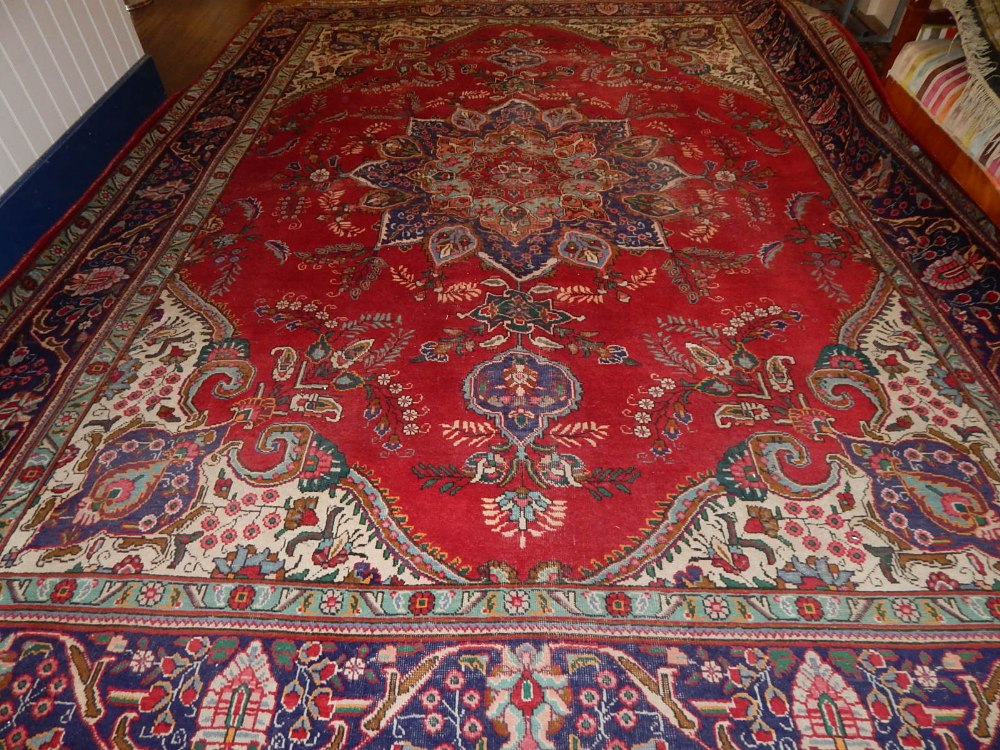 A red ground Isfahan rug, decorated with tear drop star medallion to centre, within floral