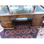 A George III style mahogany pedestal desk, with a leather inset top above an arrangement of eight