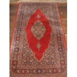 A red ground Keshan rug, decorated with tear srop medallion to centre, within floral borders, 175cm