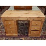 A Victorian pine kneehole desk, the rectangular plank top above an arrangement of nine drawers. W.