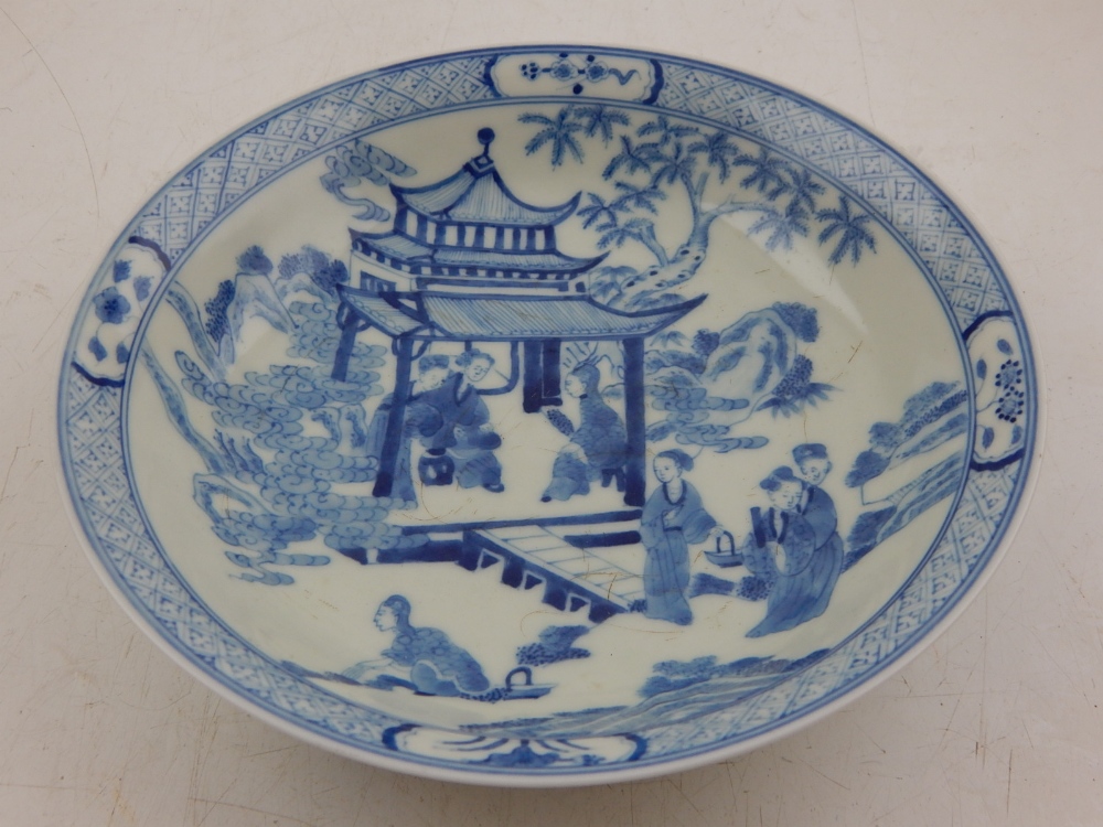 A Chinese Yongzheng style blue and white dish, decorated with women in a pagoda, bears seal mark