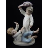 A Lladro figural study of two children pillow fighting. H. 23cm