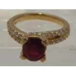An 18 carat yellow gold, diamond, and ruby ring, the oval cut ruby of approx. 0.80 carats, raised