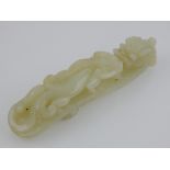 A Chinese celadon jade belt buckle, carved as two dragons. L. 11cm