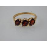 A garnet three stone ring, claw set in a 9ct gold band.