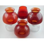 A pair of glass tea light holders, with red shades and clear glass bodies, together with an addition
