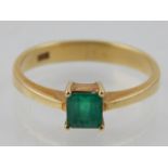 An 18 carat yellow gold and emerald solitaire ring, stamped 18k to shank