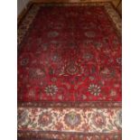 A red ground Keshan rug, decorated with tear drop medallion to centre, within cream floral border,