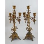 A pair of three branch gilt metal candlesticks, the central support terminating in a sconce,