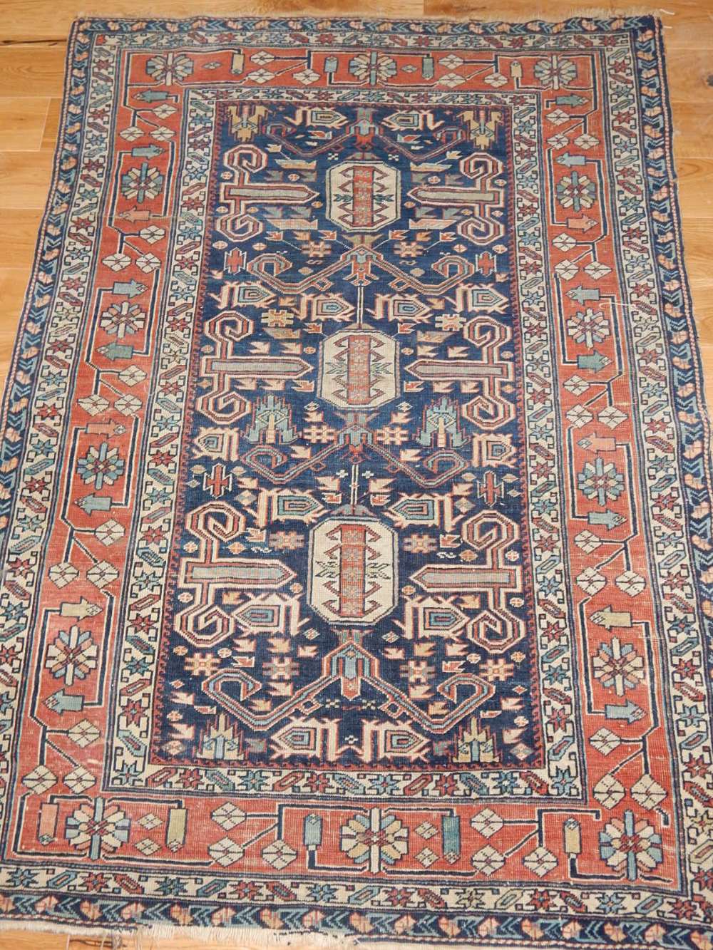 A Caucasian rug, the stylized floral design on a blue ground within a multi-panel border,