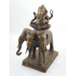 A bronze figure of ganesh, seated on a three headed elephant, H. 30cm.