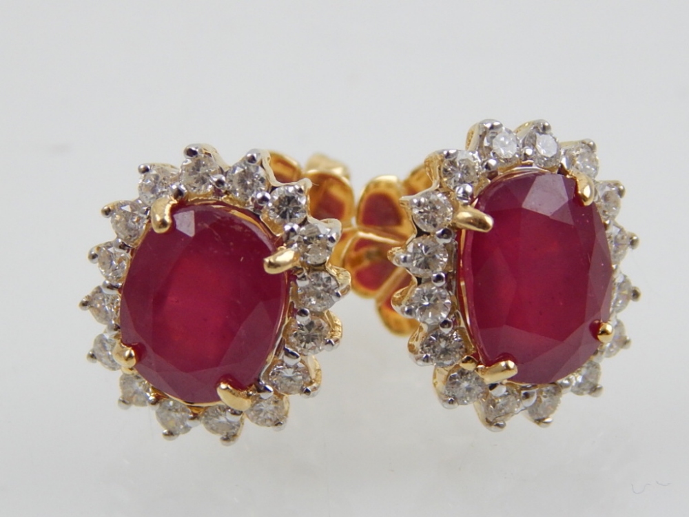 A pair of 18ct yellow gold and ruby cluster earrings, the oval cut ruby of 6.17ct, diamonds of 0.