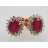 A pair of 18ct yellow gold and ruby cluster earrings, the oval cut ruby of 6.17ct, diamonds of 0.