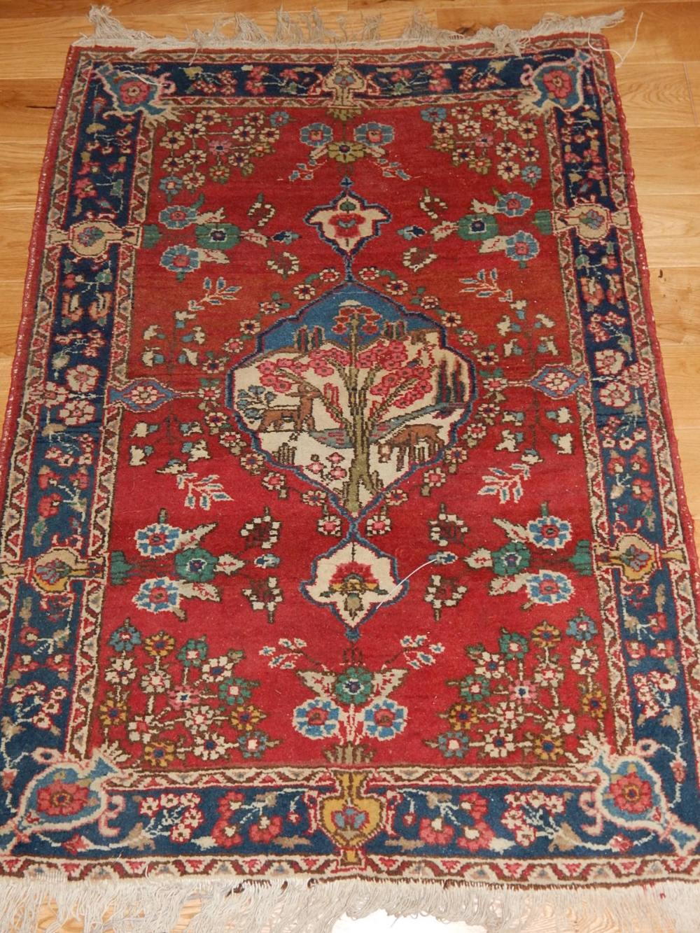 A Tabriz rug, the central pictorial medallion within flowers on a red ground, 127 x 90cm.