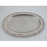 A Continental white metal dish, with embossed floral border and engraved palm trees to centre,