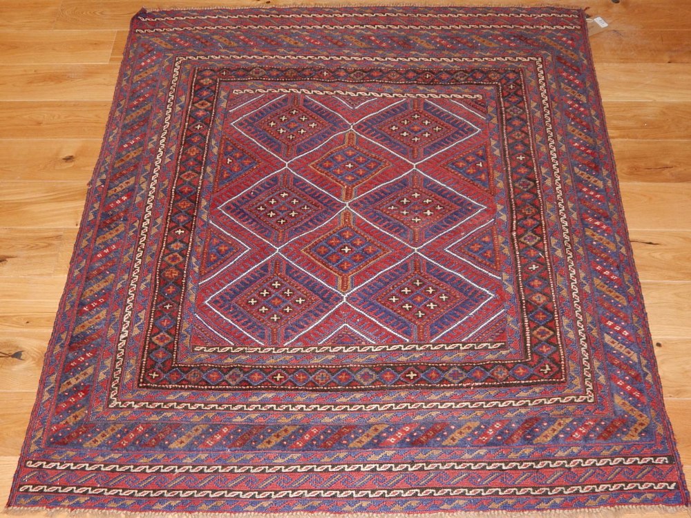 A Kazak tribal rug, blue and red with a diamond ground within a multi-panel border, 122 x 134cm.