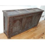 An 17th century and later plank coffer, panelled and carved with scrolling design, 73x173cm.