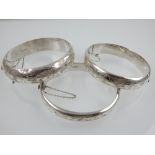 Three silver bangles, engraved with floral design,