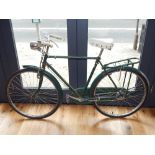 A green painted Raleigh bicycle, having bell, front lamp and saddlebag rack.