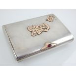 A Cypriot white metal cigarette case, with applied script to top, red cabochon latch and gilt washed