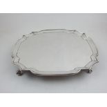 A silver card tray, London 1925, square with cusped corners and raised on ball and claw feet, 25.