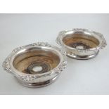 A pair of silver plated bottle coasters, with embossed foliate border. D. 17cm.